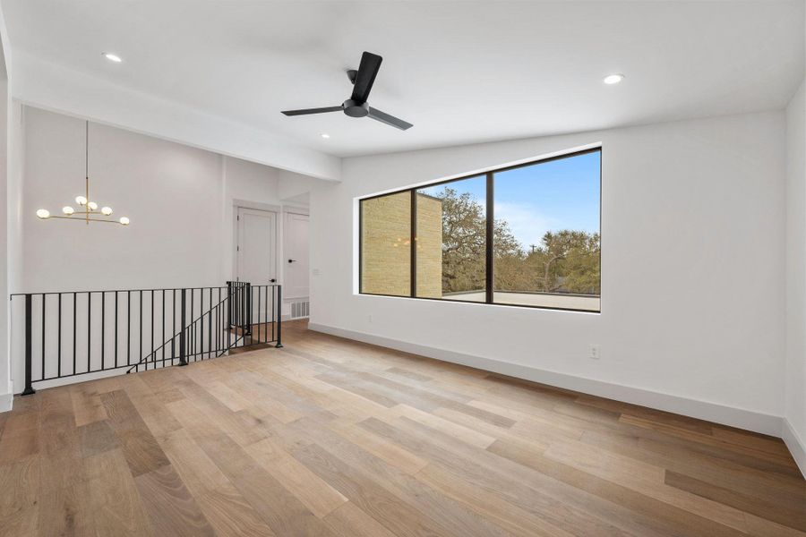 Gameroom featuring light wood-style floors, ceiling fan, suspended lighting, and vaulted ceiling