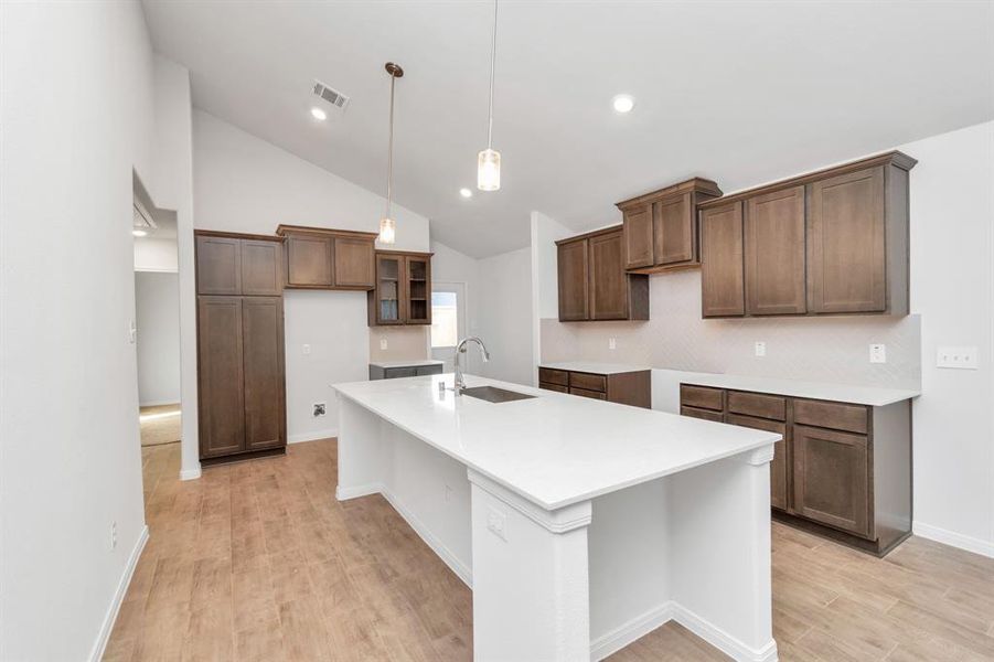 Discover a blend of elegance and functionality in this open-concept kitchen, complete with modern cabinetry and a sleek island with a sink that overlooks the spacious living area. Perfect for entertaining or everyday living, this layout ensures a seamless flow from cooking to relaxing, creating a welcoming atmosphere for family and friends alike. **This image is from another Saratoga Home - Clover floorplan.**