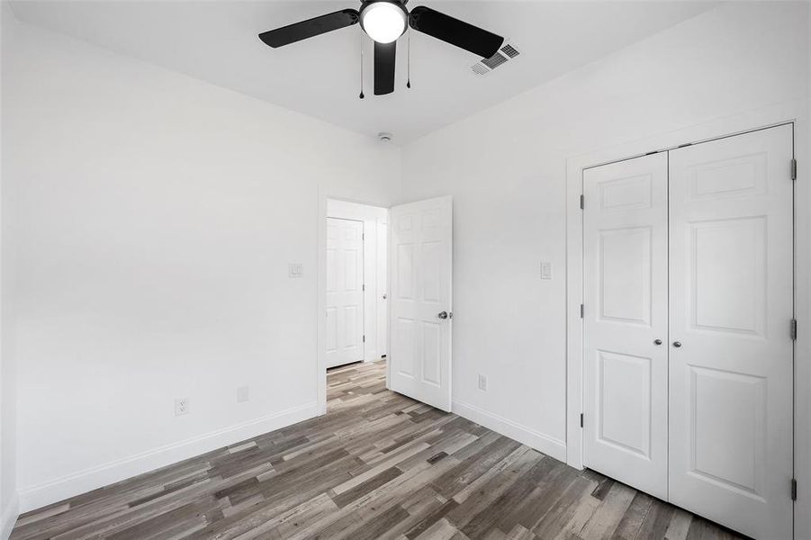 Unfurnished bedroom featuring wood finished floors, ceiling fan, and a closet