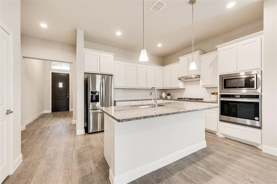 Kitchen with tasteful backsplash, stainless steel appliances, white cabinets, and recessed lighting
