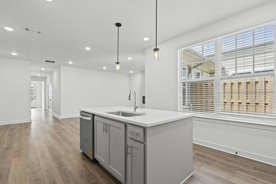 Central kitchen island featuring a stainless steel sink and gooseneck faucet