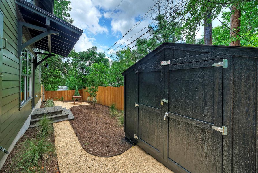 A private yard with a gravel path leads to a large storage shed and well-maintained landscaping.
