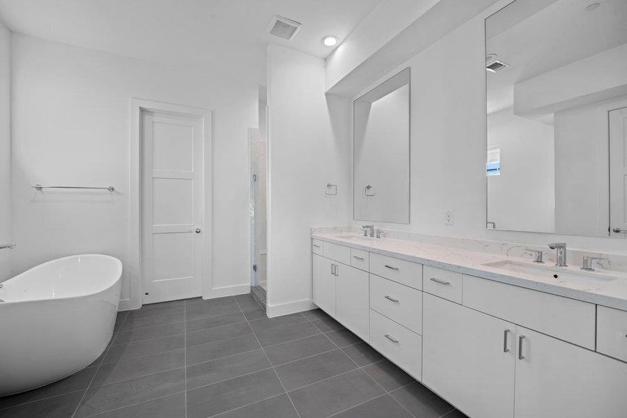 Full bath with a soaking tub, dark tile patterned floors, double vanity, and recessed lighting