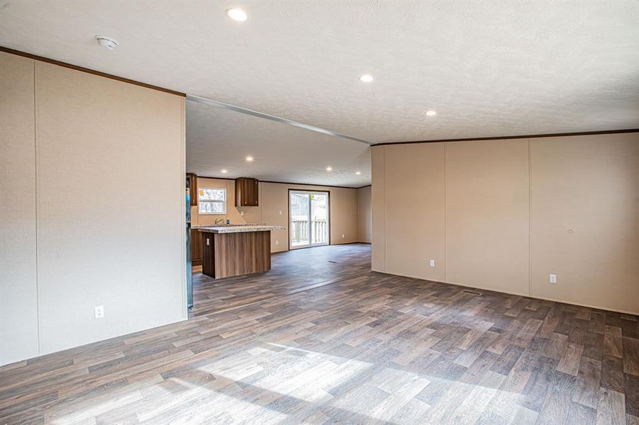 Unfurnished living room featuring crown molding, recessed lighting, dark wood-type flooring, and a textured ceiling Unfurnished living room featuring crown molding, recessed lighting, dark wood-type flooring, and a textured ceiling
