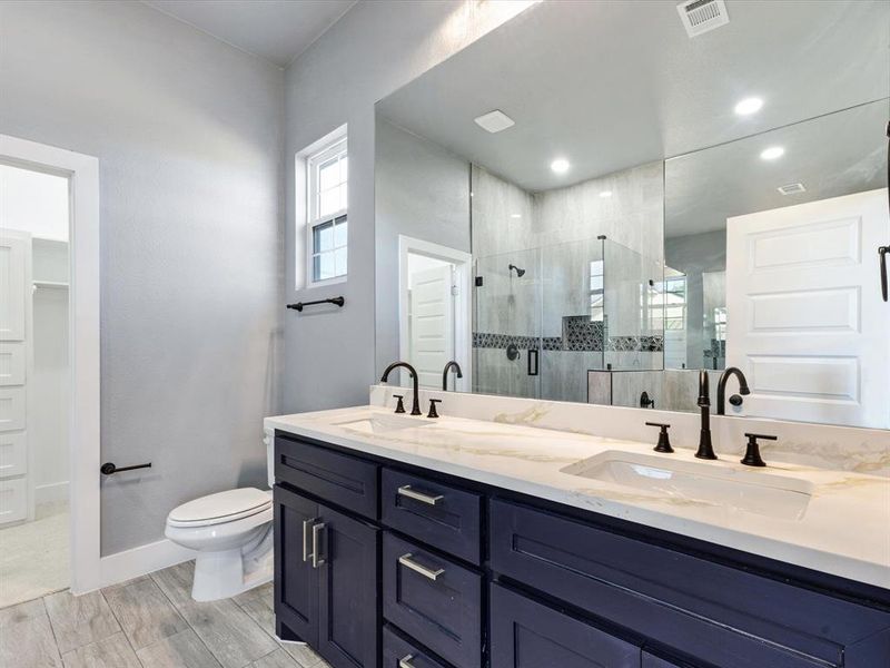 Full bathroom with double vanity, a shower stall, and wood finish floors Full bathroom with double vanity, a shower stall, and wood finish floors