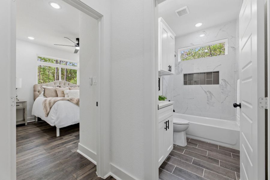 Elegant white tile bathroom and bedroom combo, a modern design with large windows offering ample natural light.