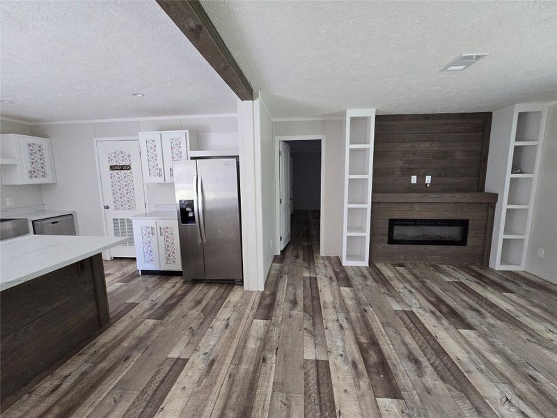 Experience seamless living with this open-concept kitchen and living room, featuring rustic wood flooring, sleek modern appliances, and a cozy fireplace, creating the perfect blend of style and comfort. Experience seamless living with this open-concept kitchen and living room, featuring rustic wood flooring, sleek modern appliances, and a cozy fireplace, creating the perfect blend of style and comfort.