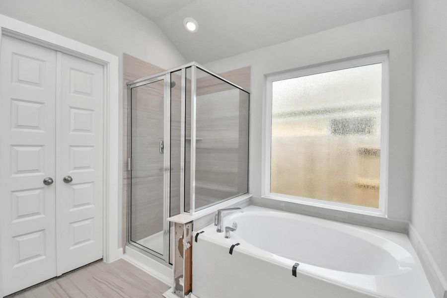 Indulge in a spa-like retreat within the confines of this primary bathroom. Delight in a spacious walk-in shower enveloped in stylish tile surround and unwind in a separate garden tub adorned with custom detailing.