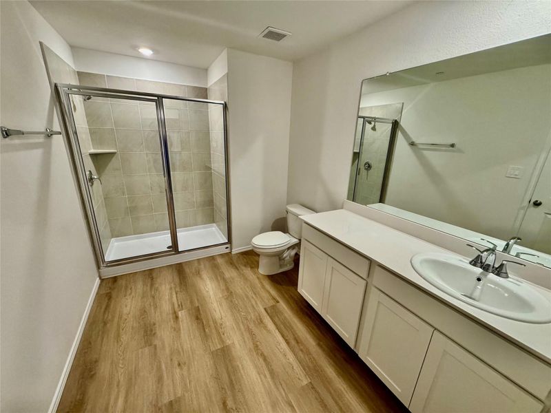 Full bath featuring vanity, a shower stall, and light wood finished floors