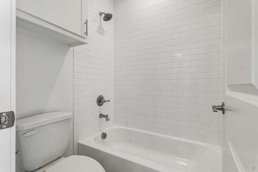 Bathroom featuring tiled shower / bath combo and toilet
