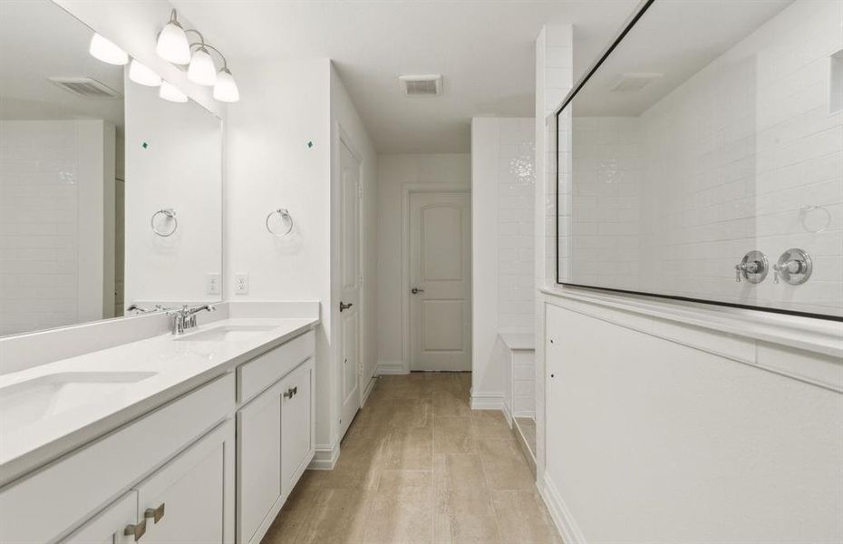 Modern owner's bath with dual vanities and a spacious shower *Real home pictured