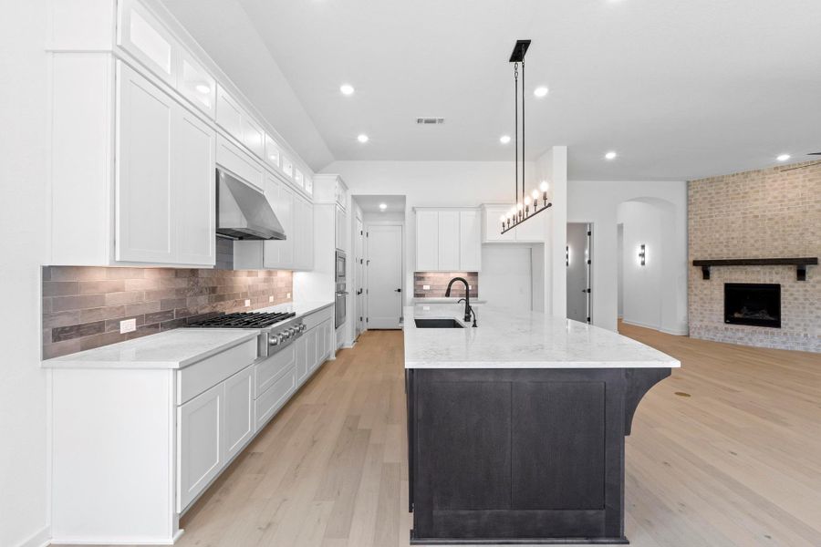 Kitchen featuring light wood finished floors, tasteful backsplash, open floor plan, light stone countertops, and recessed lighting