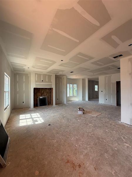 Expansive interior space featuring a central fireplace surround and tray ceilings Expansive interior space featuring a central fireplace surround and tray ceilings