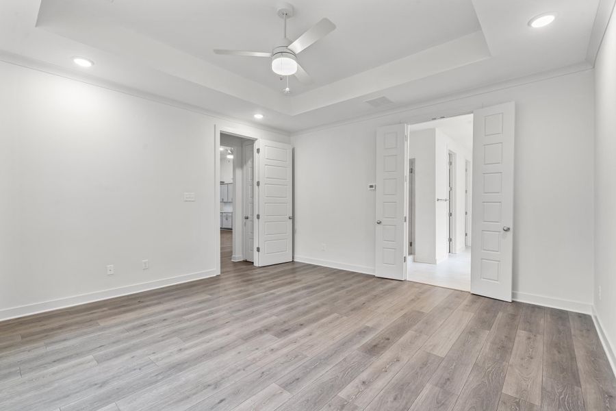 Unfurnished bedroom with recessed lighting, a tray ceiling, light wood-style floors, ceiling fan, and crown molding