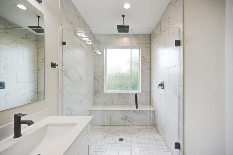 Large oversized shower with rain shower head and shower bench.