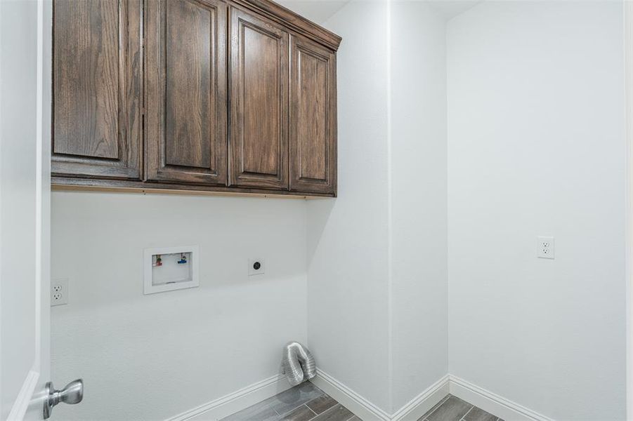 Laundry area with cabinet space, baseboards, wood finished floors, hookup for a washing machine, and hookup for an electric dryer