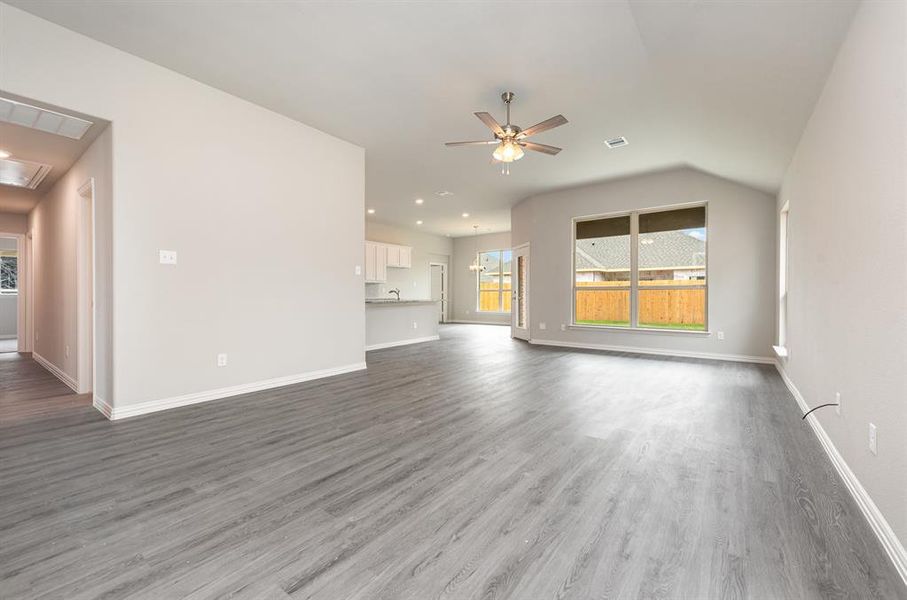 Unfurnished living room with hardwood / wood-style flooring, vaulted ceiling, and ceiling fan