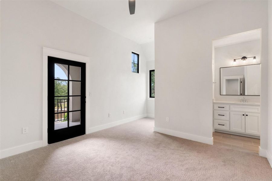 A light-filled primary bedroom with vaulted ceilings and direct access to a private balcony, complemented by an en-suite bathroom.