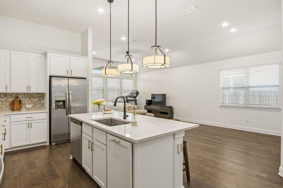 Kitchen with white cabinetry, dark wood-style flooring, open floor plan, a kitchen island with sink, and appliances with stainless steel finishes