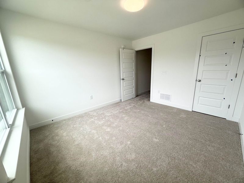 Unfurnished bedroom with carpet flooring and baseboards Unfurnished bedroom with carpet flooring and baseboards