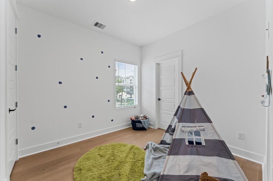 This secondary bedroom on the second floor exudes warmth and sophistication with its rich engineered hardwood flooring, adding a touch of elegance to the space. The smooth, durable surface enhances the room’s clean lines and complements a variety of décor from cozy and traditional to sleek and modern. Natural light dances across the wood grain, creating a serene atmosphere ideal for rest, work, or creative pursuits.