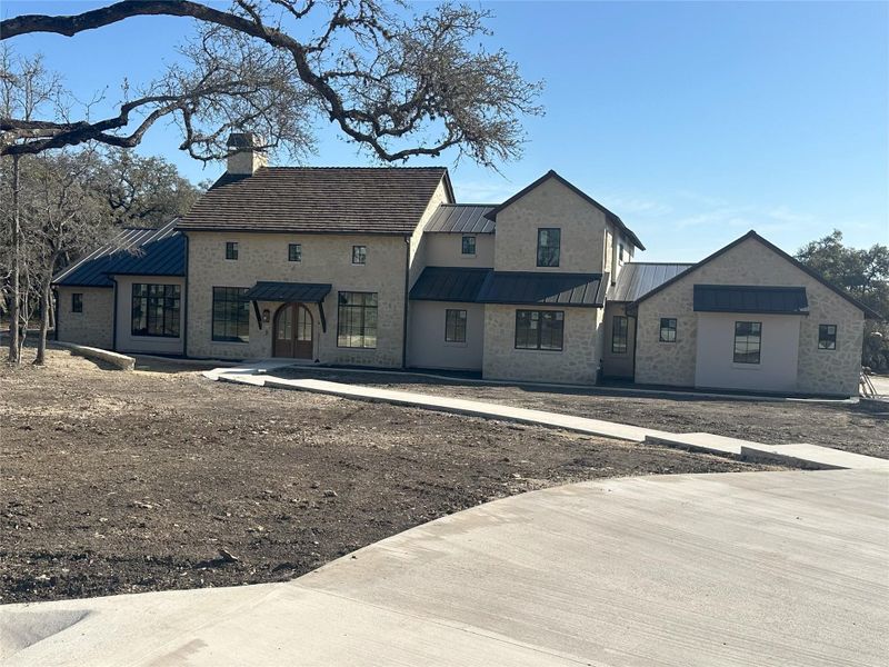 View of front of property featuring metal roof, stone siding, a standing seam roof, and a chimney