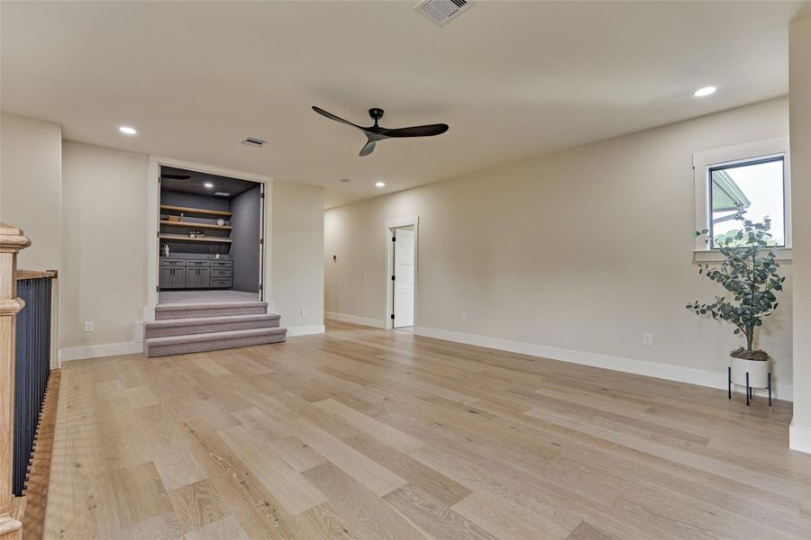 Wide-open game room flowing to the secondary bedrooms, framed by an iron-and-wood staircase railing — bright, open, and ready for everyday living. Wide-open game room flowing to the secondary bedrooms, framed by an iron-and-wood staircase railing — bright, open, and ready for everyday living.
