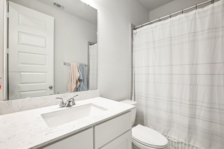 Bathroom featuring a textured wall, a shower with curtain, and vanity