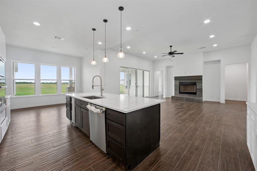 Kitchen with recessed lighting, open floor plan, a tiled fireplace, appliances with stainless steel finishes, and decorative light fixtures