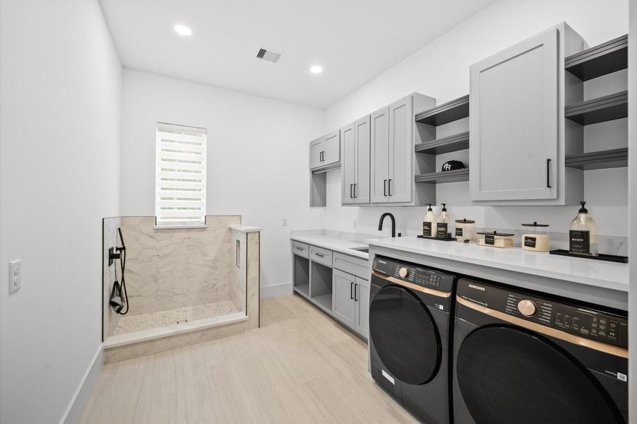 Oversized utility room featuring extensive custom cabinetry and separate pet wash area that adds everyday convenience.