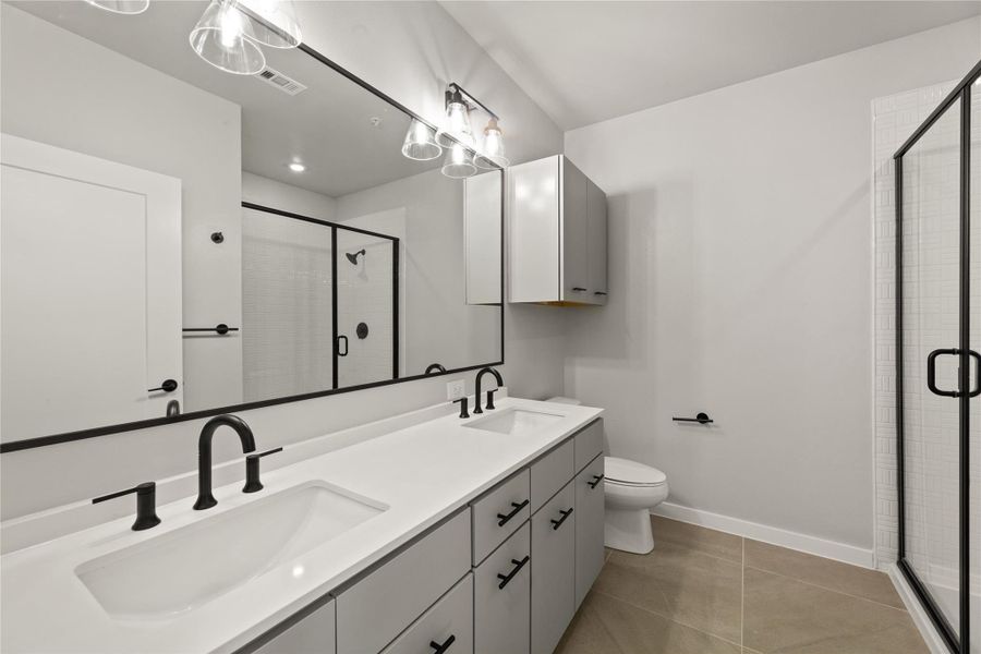 Full bath featuring double vanity, a shower stall, and tile patterned floors