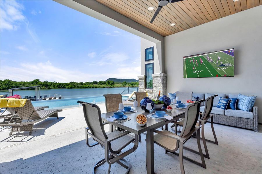 Covered outdoor living space featuring outdoor kitchen for lakeside dinners and panoramic water frontage.