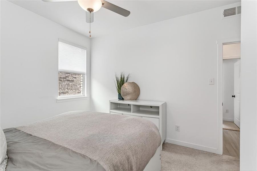Well-lit room with a window, ceiling fan, and light-colored carpeting