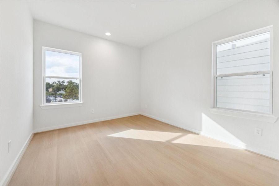 Secondary bedroom adjacent to the third-floor game room, featuring abundant natural light and a versatile layout, perfect for guests, a home office, or a private retreat.
