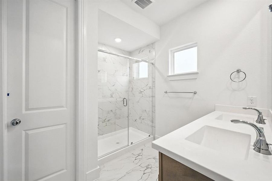 Full bathroom featuring light marble finish floors, a marble finish shower, double vanity, and recessed lighting Full bathroom featuring light marble finish floors, a marble finish shower, double vanity, and recessed lighting