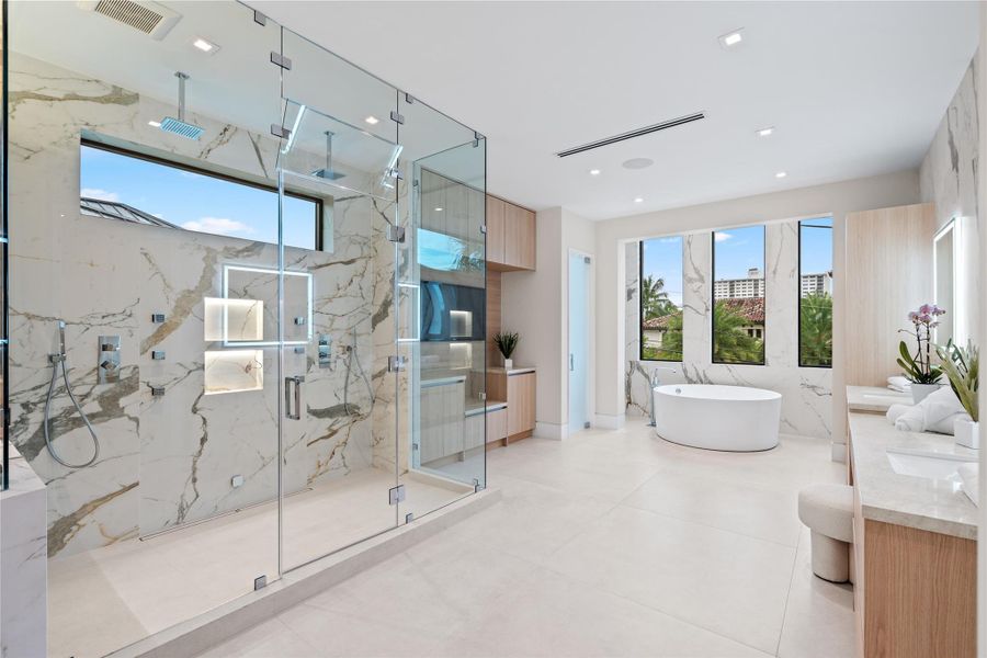 Elegant primary bathroom with a glass-enclosed double rainfall shower, freestanding soaking tub, and floor-to-ceiling windows bringing in natural light. Elegant primary bathroom with a glass-enclosed double rainfall shower, freestanding soaking tub, and floor-to-ceiling windows bringing in natural light.