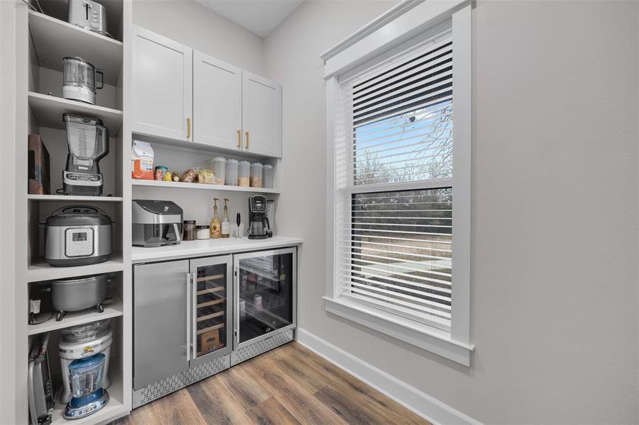 Bar featuring white cabinetry, beverage cooler, and hardwood / wood-style flooring