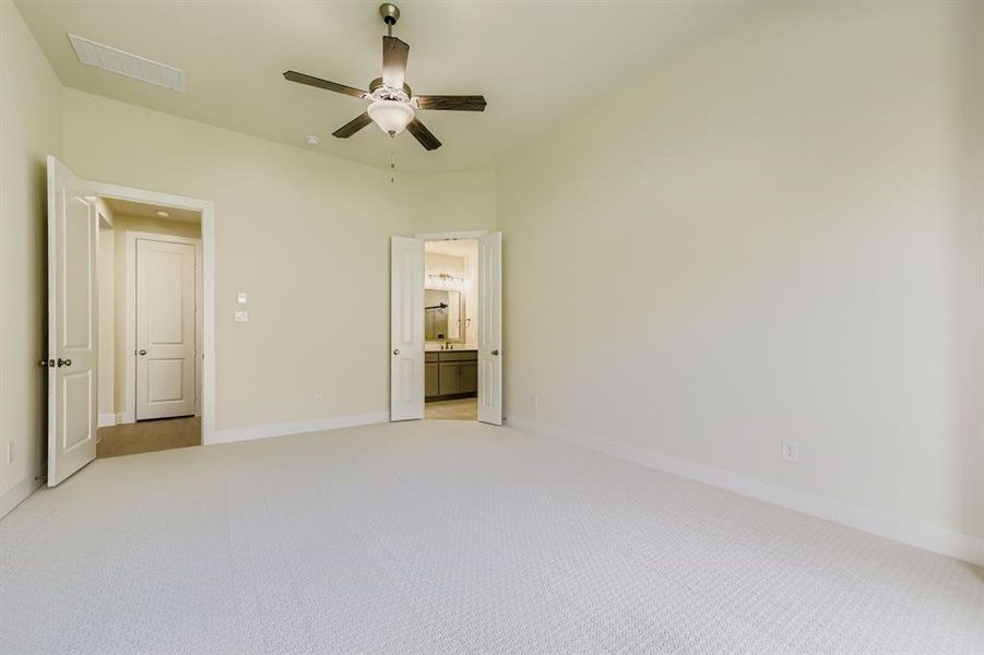 Unfurnished bedroom with light carpet, ensuite bath, and ceiling fan