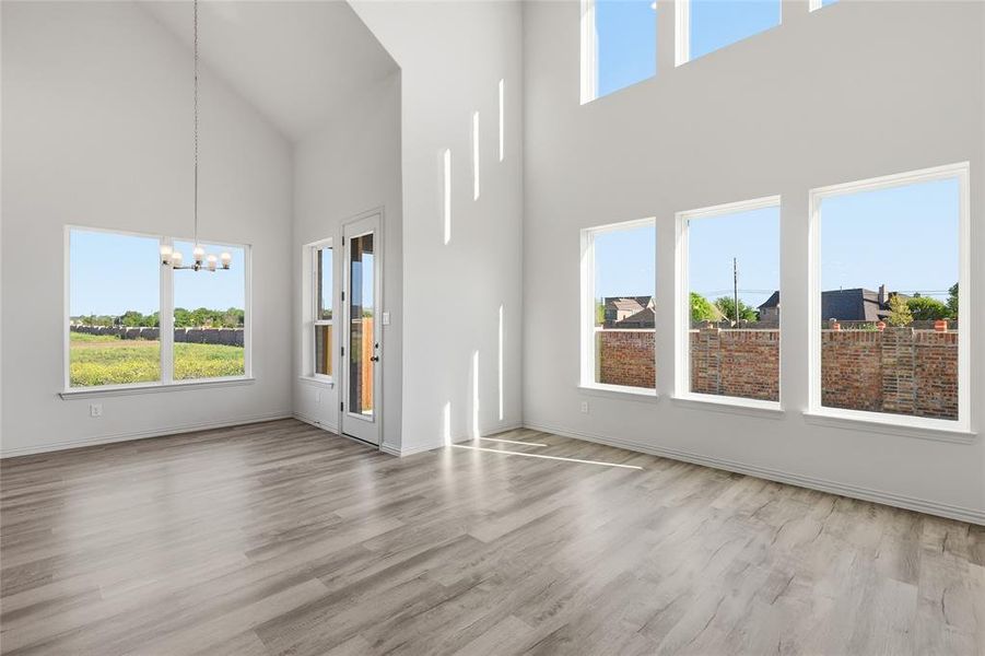 Unfurnished living room featuring a chandelier, light wood finished floors, and vaulted ceiling Unfurnished living room featuring a chandelier, light wood finished floors, and vaulted ceiling