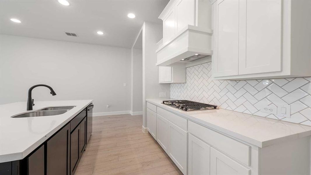 Kitchen featuring white cabinetry, light hardwood / wood-style flooring, backsplash, appliances with stainless steel finishes, and sink