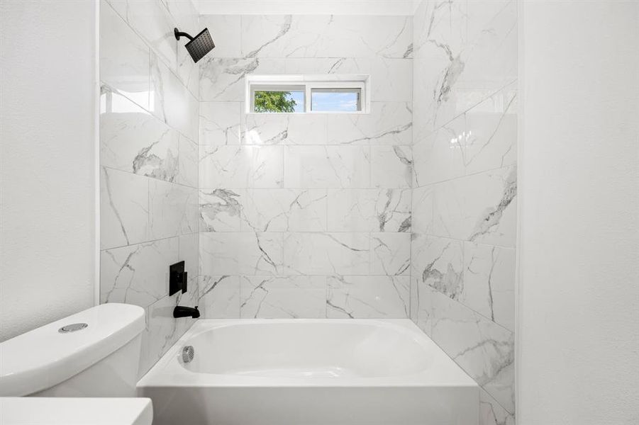 Bathroom with toilet and tiled shower / bath