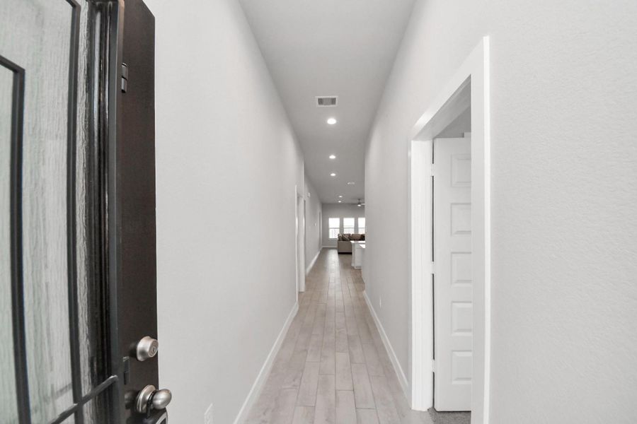 Welcome Home! Entryway with high ceilings, recessed lighting, and wood-look tile flooring. Door on the right leads to the 4th bedroom with its own private ensuite bathroom.