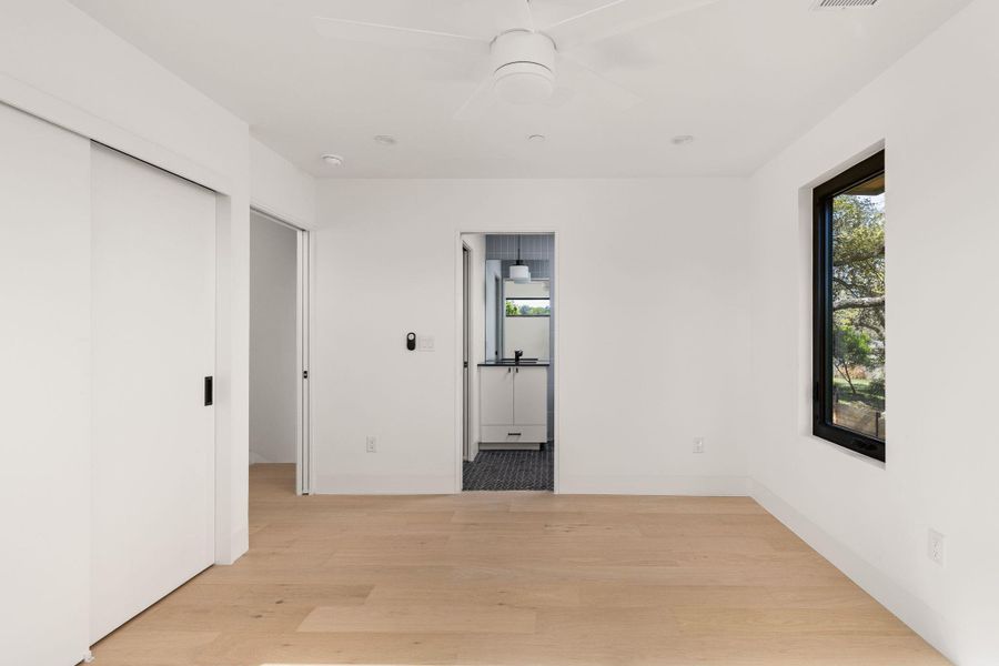 Unfurnished bedroom with light wood-style floors, a closet, a ceiling fan, and ensuite bathroom