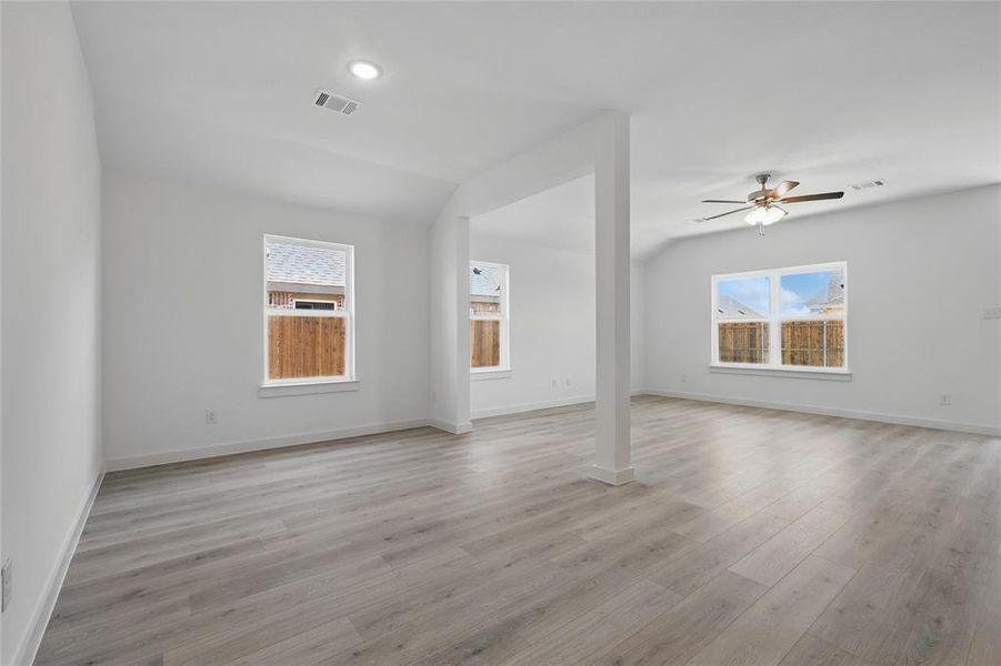 Unfurnished living room featuring light wood-style floors, a ceiling fan, and vaulted ceiling