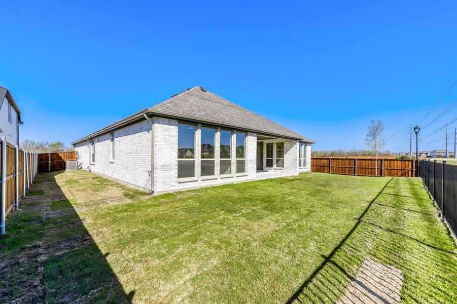 Back of house with brick siding, a fenced backyard, a patio area, and a shingled roof