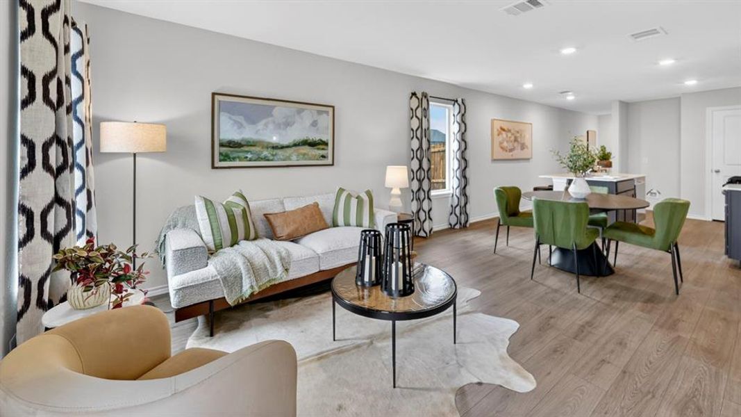 Open-concept living and dining area featuring wood-finish flooring, recessed lighting, and large windows with patterned curtains Open-concept living and dining area featuring wood-finish flooring, recessed lighting, and large windows with patterned curtains