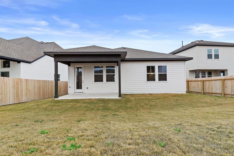 Rear view of house with a yard and a patio