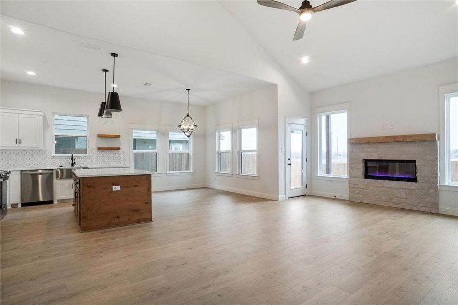 Kitchen with white cabinetry, hanging light fixtures, light hardwood / wood-style flooring, stainless steel dishwasher, and a kitchen island