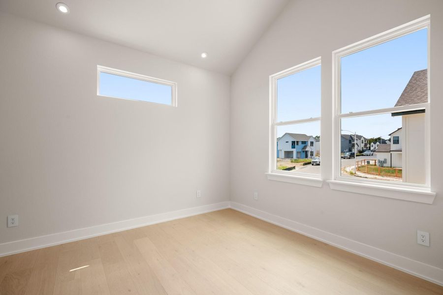 Empty room with recessed lighting, light wood finished floors, vaulted ceiling, and a residential view Empty room with recessed lighting, light wood finished floors, vaulted ceiling, and a residential view