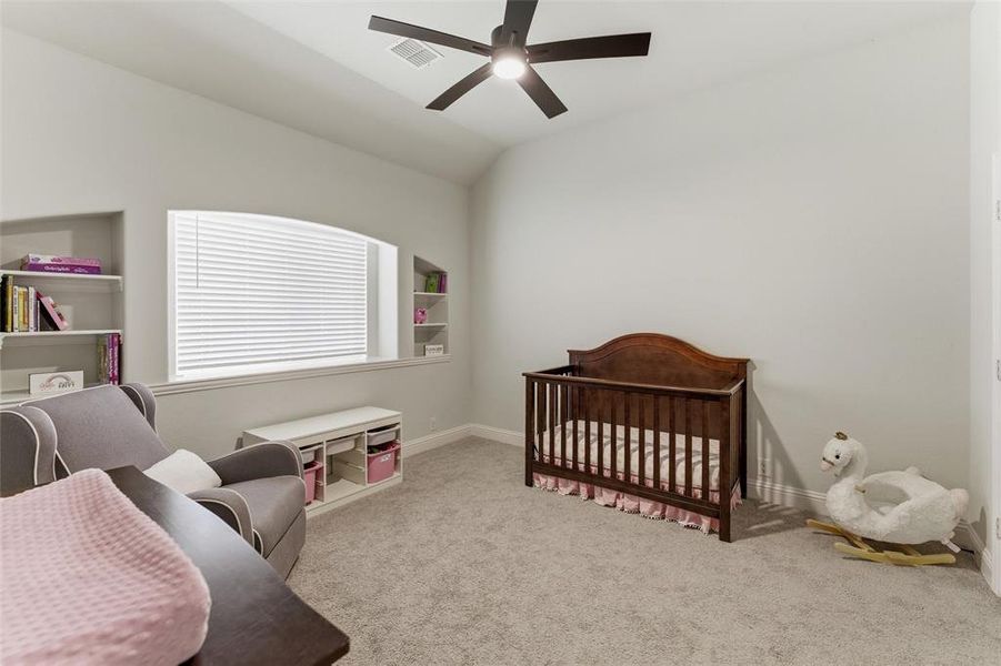Bedroom with a nursery area, light carpet, lofted ceiling, and a ceiling fan